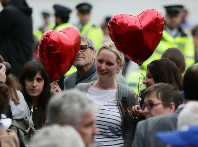 A woman holds up heart-shaped balloons during a vigil in London