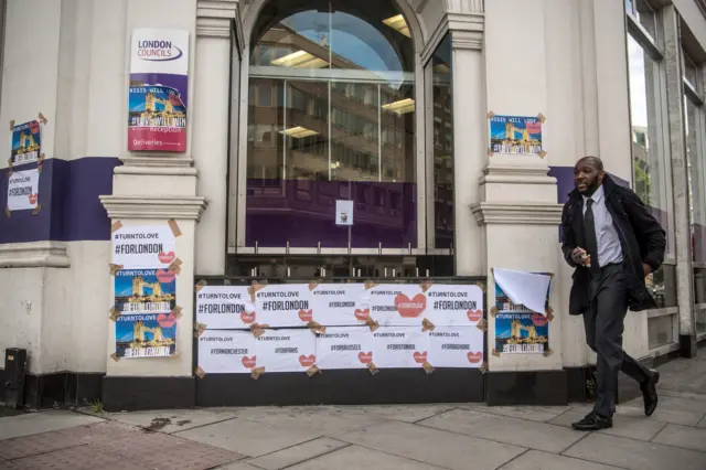 A man walks past posters pasted on a wall following Saturday's attack