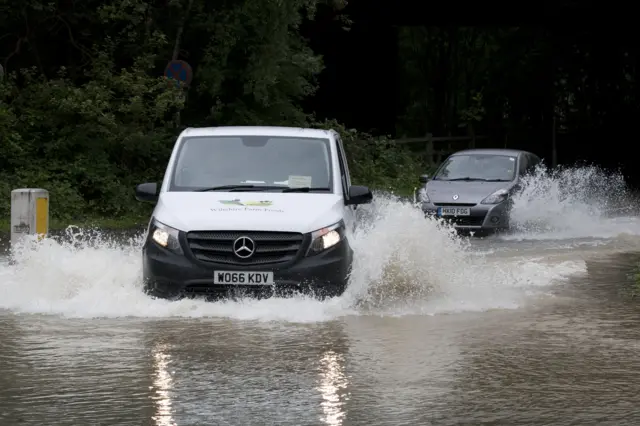 Two cars wade through flooded road