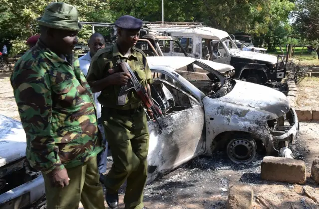 Kenya police observe the remains of burnt-out cars at a police station in Mpeketoni, Lamu county on June 16, 2014 after some 50 heavily-armed gunmen attacked the town near the coastal island and popular tourist resort of lamu the night befor