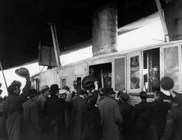 Black and white photograph showing people cheering pilot and crew of R34 airship on its arrival at Pulham