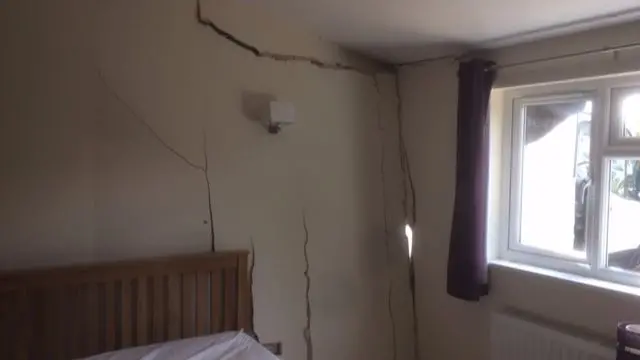 Big cracks in a bedroom wall from where a van struck the outer wall.