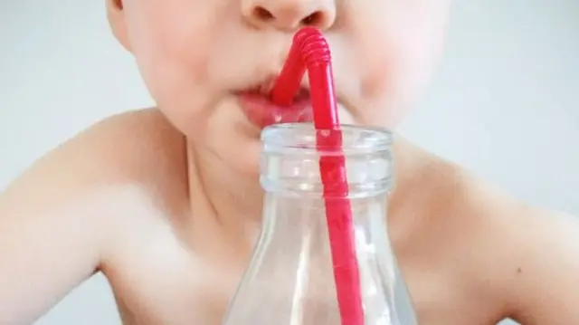 A child sucking a plastic straw