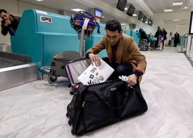 A Libyan traveller packs his laptop in his suitcase before boarding his flight for London at Tunis-Carthage International Airport on March 25, 2017.