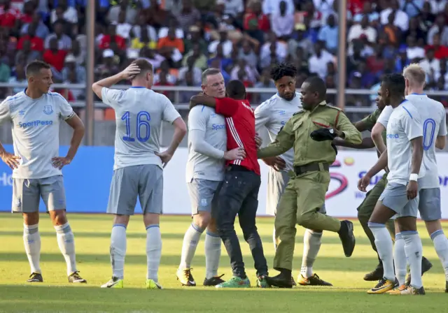 Pitch invader hugs Rooney as team mates look on