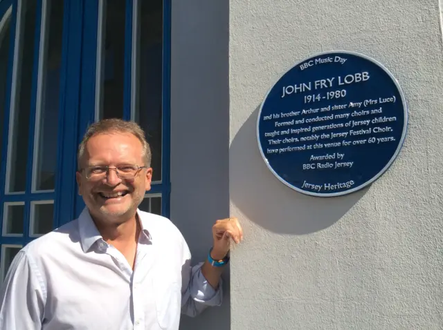 Minister Reverend Tony Morling next to blue plaque