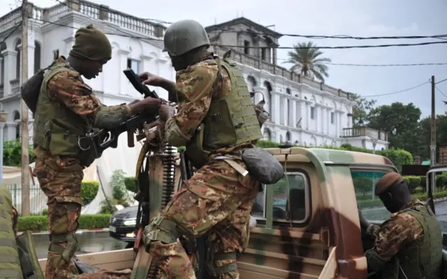 Malian soldiers stand guard in a military vehicle, outside the presidential palace in Bamako