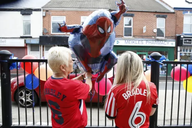 Mourners wearing football shirts decorate the streets