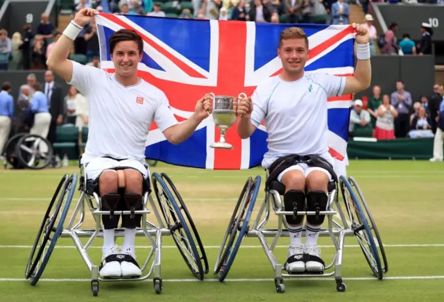 Gordon Reid and Alfie Hewett, on court, holding the winner's trophy and a Union flag