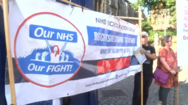 Protestors with banner outside the meeting