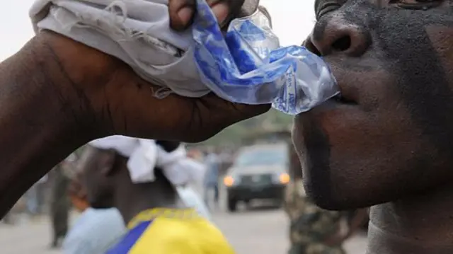 Man drinking a sachet of water