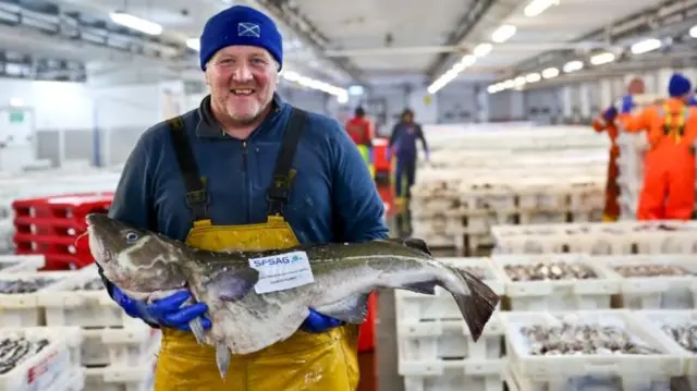 Fisherman holding a cod.