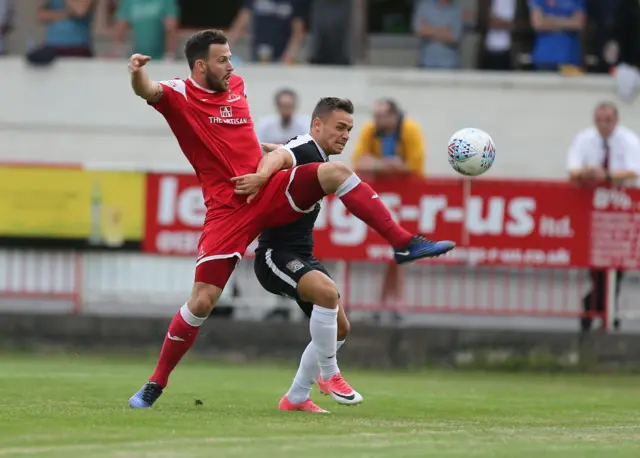 Northampton Town's Billy Waters competes with Marcus Mapstone of Frome Town for possession