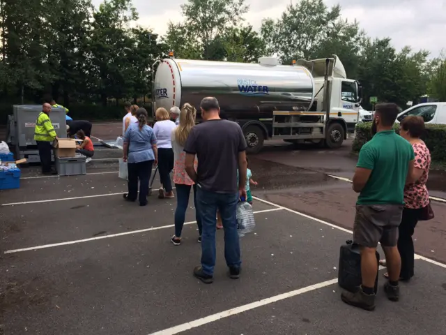 Water tanker and people queuing