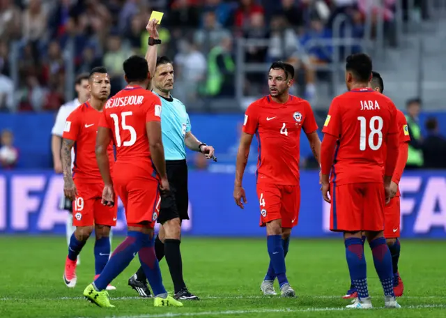 Gonzalo Jara of Chile is shown a yellow card