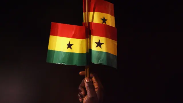 A man holds Ghanaian flags up in the air