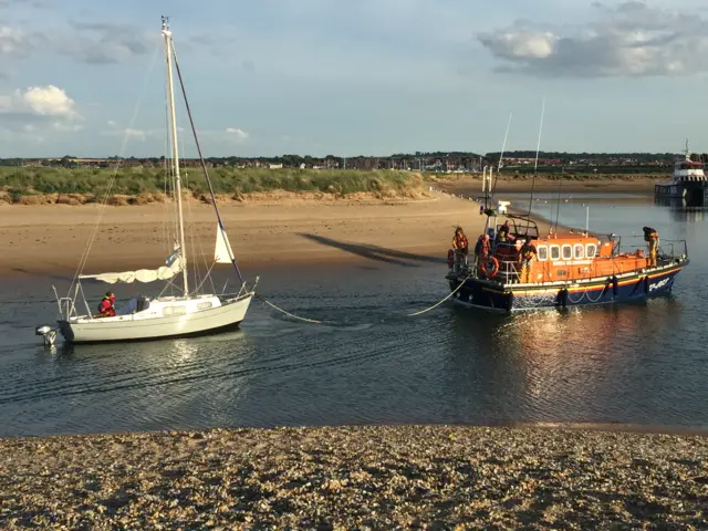 The yacht being towed into Wells harbour