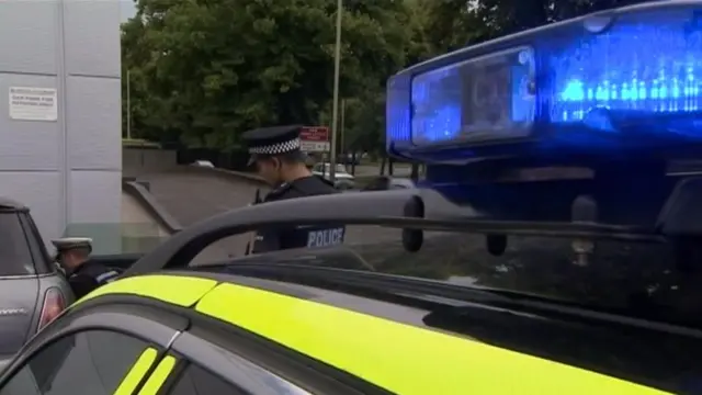 Police officers and police vehicle, with one officer talking to a motorist in their car