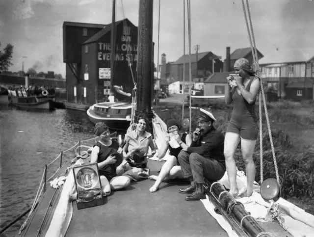 Black and white photo of the holidaymakers with musical instruments on deck