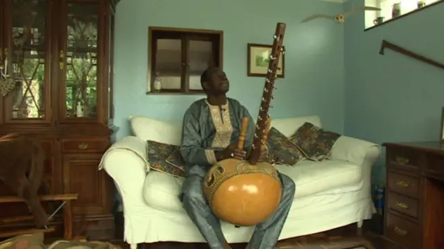 Sefo, seated, playing the kora