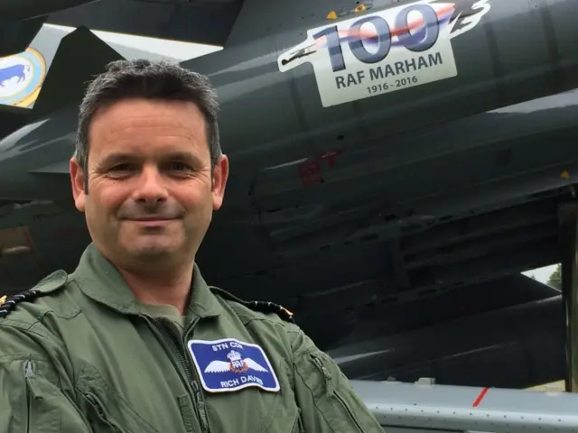 Gp Capt davies stands by plane, with logo marking 100th year