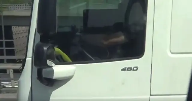 Lorry driver watching a laptop behind the wheel