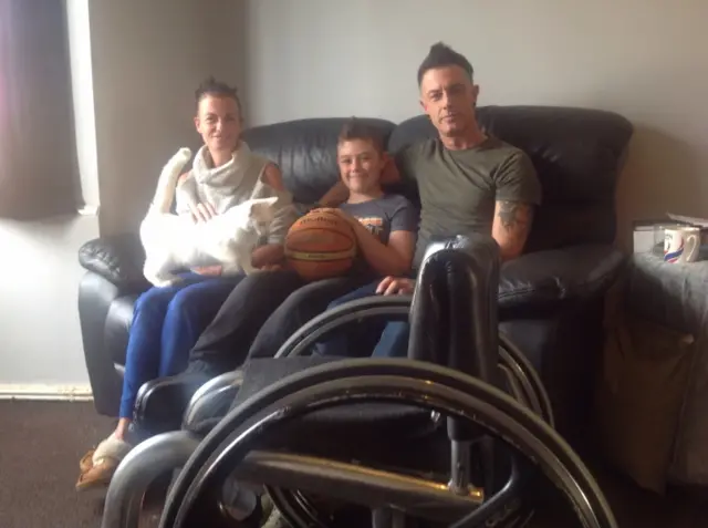 Mum Victoria, Dan and dad Matt sit on sofa, with Dan's wheelchair in front of them