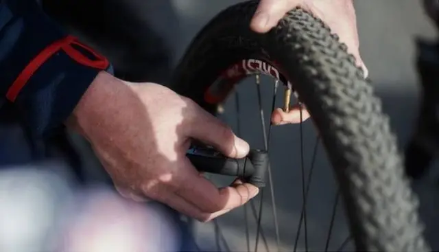 close up of a man's hands on a bike wheel trying to find a puncture