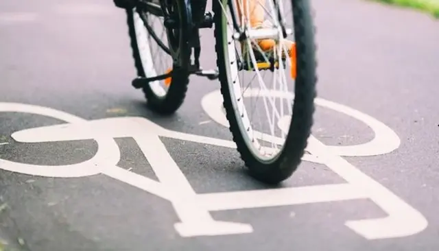 Close up of the wheels of a bike going over a cycling path sign painted onto the road