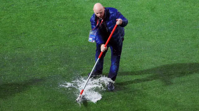 Ground staff try to clear the surface water