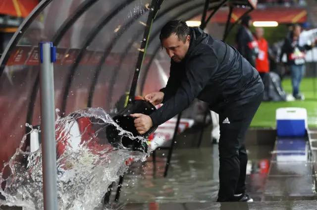 A groundsman empties the dugouts of water