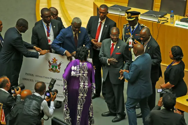 Zimbabwe's President, Robert Mugabe (C) gives a 1 million USD cheque to the African Union Foundation during the 29th African Union Summit in Addis Ababa