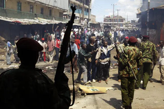 Kenyan police talk to protestors during clashes between two rival groups due to the results of Kenya's disputed presidential election.