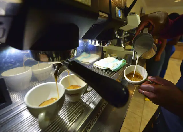 A coffee barista shows how to pour milk in a coffee in what is commonly known as 'latte art' or 'coffee art' at Dormans cafe in Nairobi on April 25, 2016.