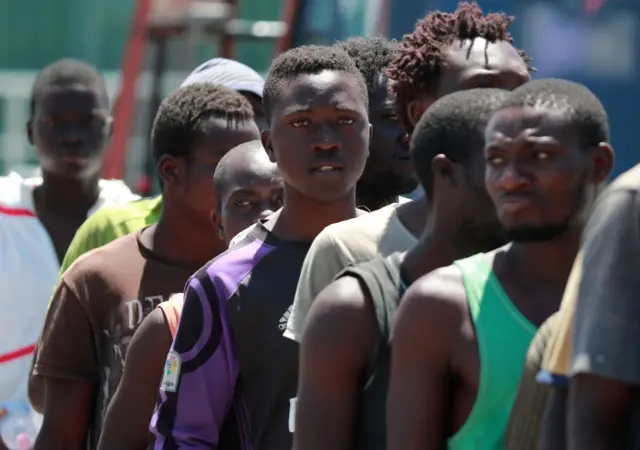 Migrants wait in line as they disembark from the Spanish Guardia Civil Rio Segura Patrol Ship with 1,216 migrants onboard including 256 children and 11 pregnant women, who were rescued in the Mediterranean sea on June 29, 2017, in the port of Salerno