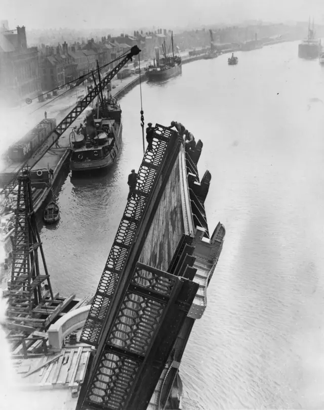 Black and white photo showing workmen on the cantilever bridge