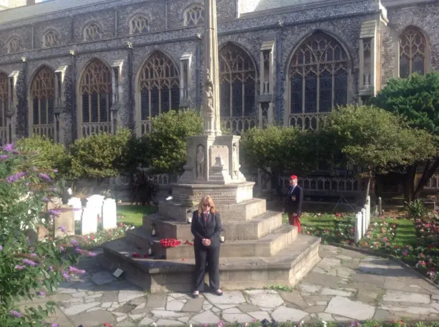 The war memorial outside the church, with two people paying their respects