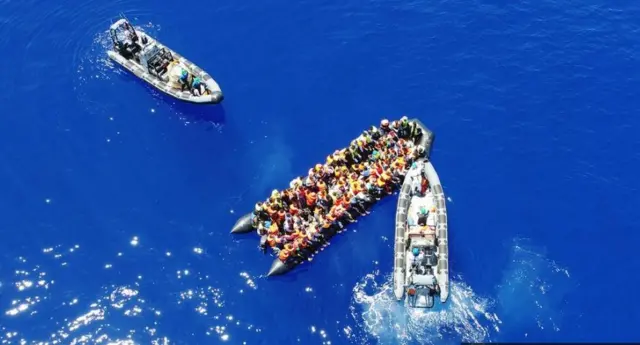 Navy boat rescuing migrant boat