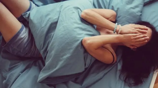 A woman in bed with her head in her hands