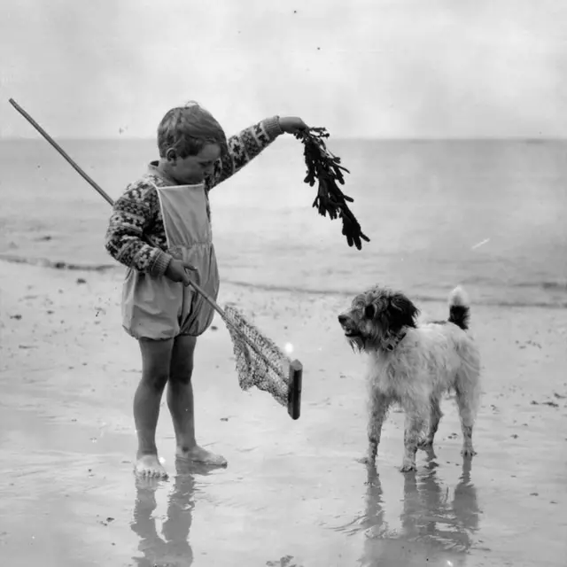 July 1926: A young child with his dog on the beach at Lowestoft.