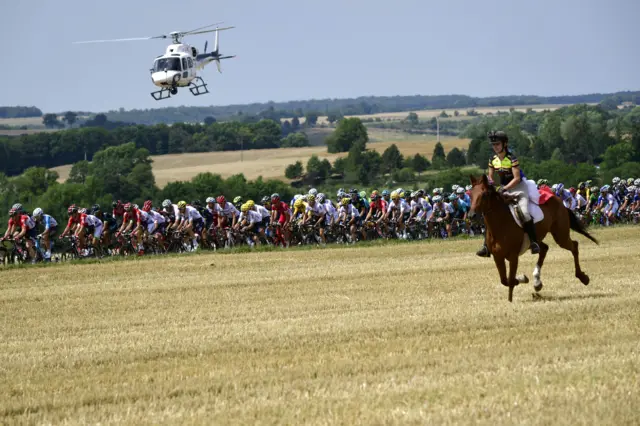 The peloton ride alongside a horse rider