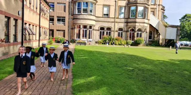 School children walking barefoot around the grounds