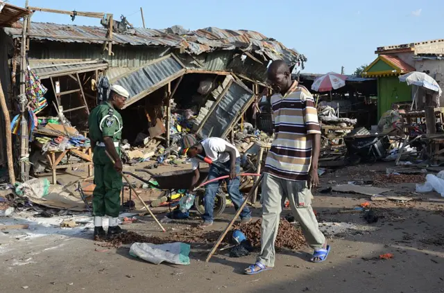 A man walks past a the scene of a bombing after at least 20 people were killed when a young female suicide bomber detonated her explosives at a bus station in Maiduguri, northeast Nigeria, on June 22, 2015 in an attack likely to be blamed on Boko Haram