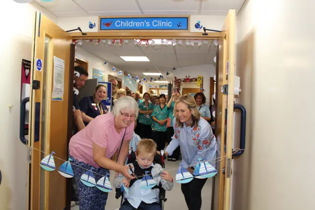 Eight-year-old patient Drew Bye and former staff member Rachel Short cutting the string of paper boats