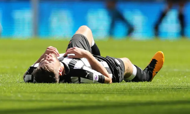 Paul Dummett lies injured on the pitch