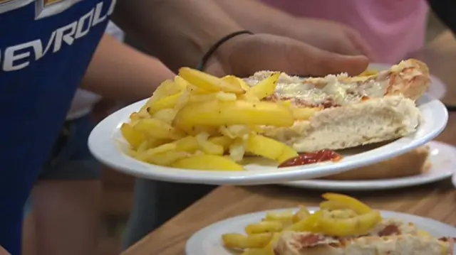 A child holding chips and pizza on a plate