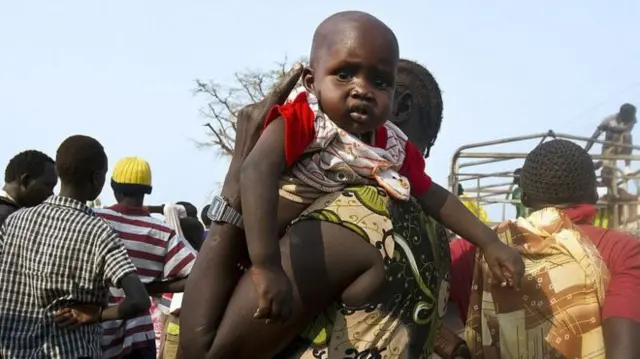 A woman holds a baby as refugees from South Sudan wait to board a truck at Dzaipi Refugee Transit Centre in Adjumani, northern Uganda, to be transferred to nearby Nyumanzi Resettlement CampImage copyrightAFP Image caption The UN says that 85% of the refugees who have arrived in Uganda are women and children