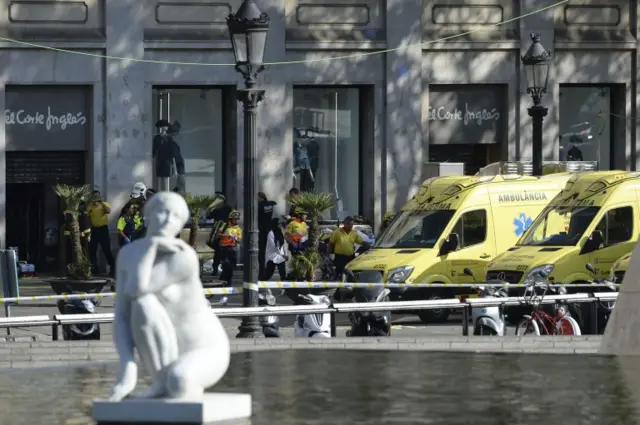 Medical staff members and policemen stand in a cordoned off area after a van ploughed into the crowd, injuring several persons on the Rambla in Barcelona