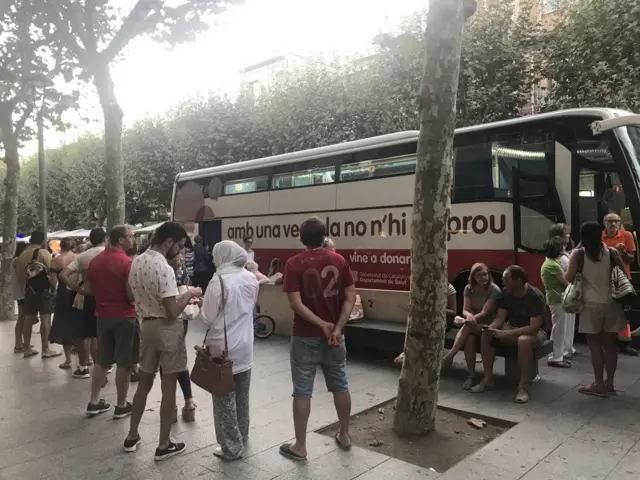 People are pictured by a blood donation van queuing