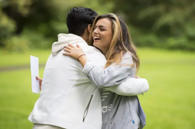 Vicky Baker (R) hugs Abu Latif after receiving their AS Level results at Ffynone House School in Swansea